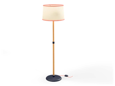 Tall floor lamp with a glowing cream drum shade with coral trim on a thin wooden pole and dark round base